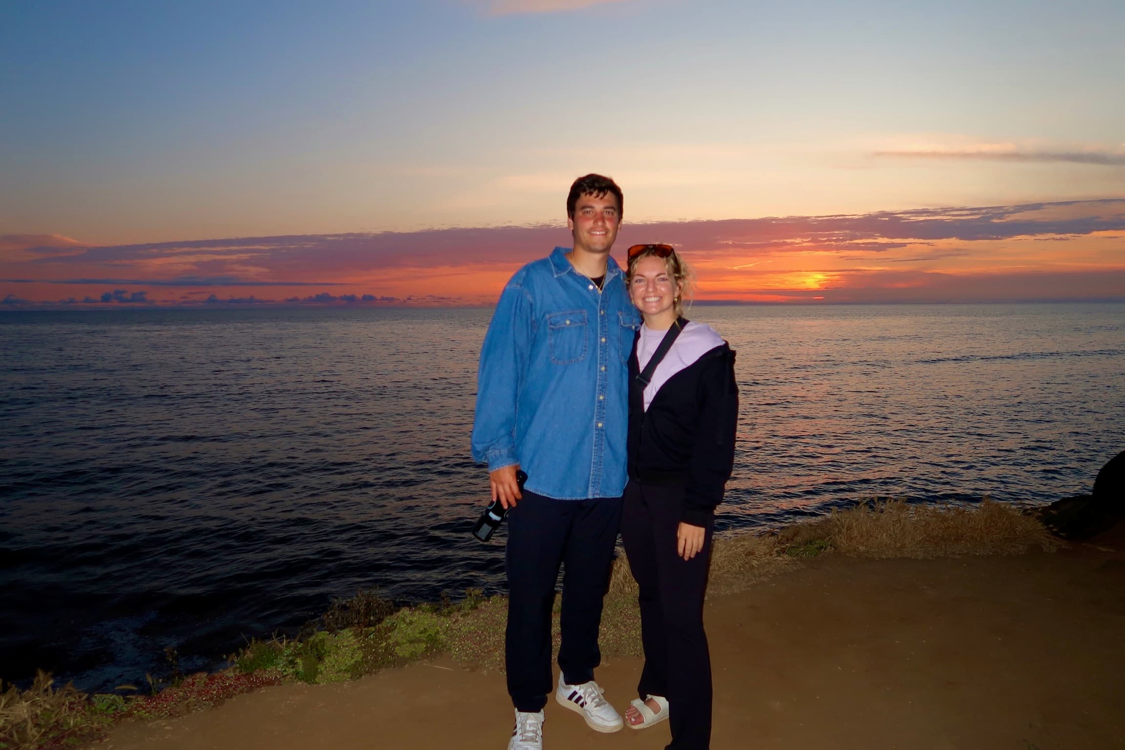 Adam Preda with a companion by the ocean at sunset in San Diego